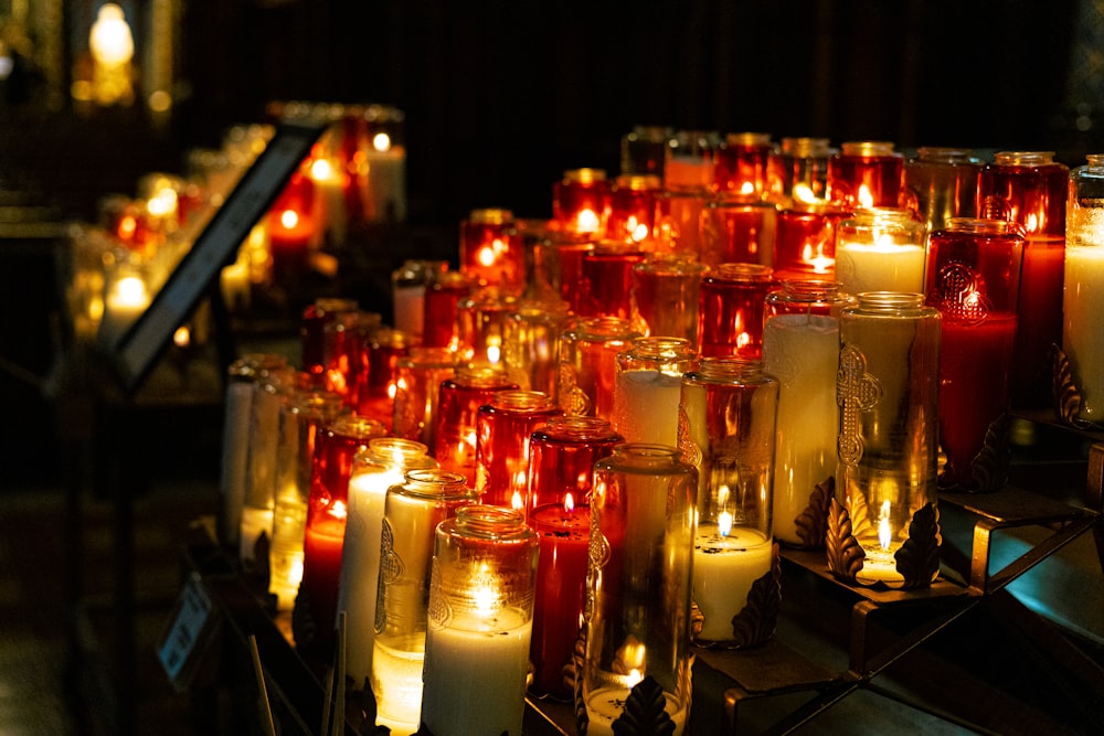 many lit candles are lined up on a table