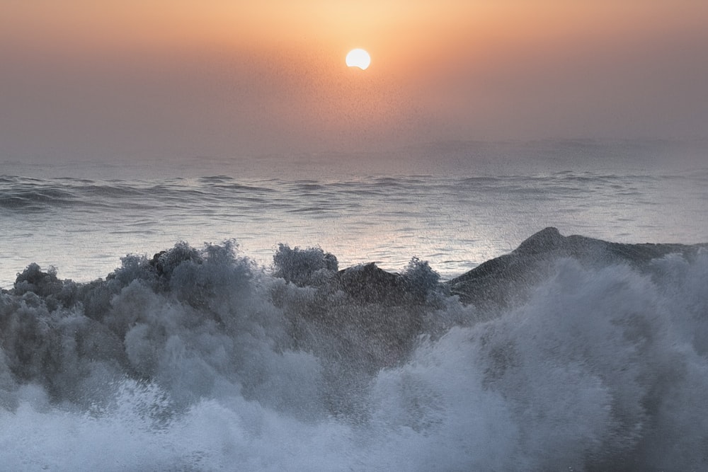 the sun is setting over the ocean waves