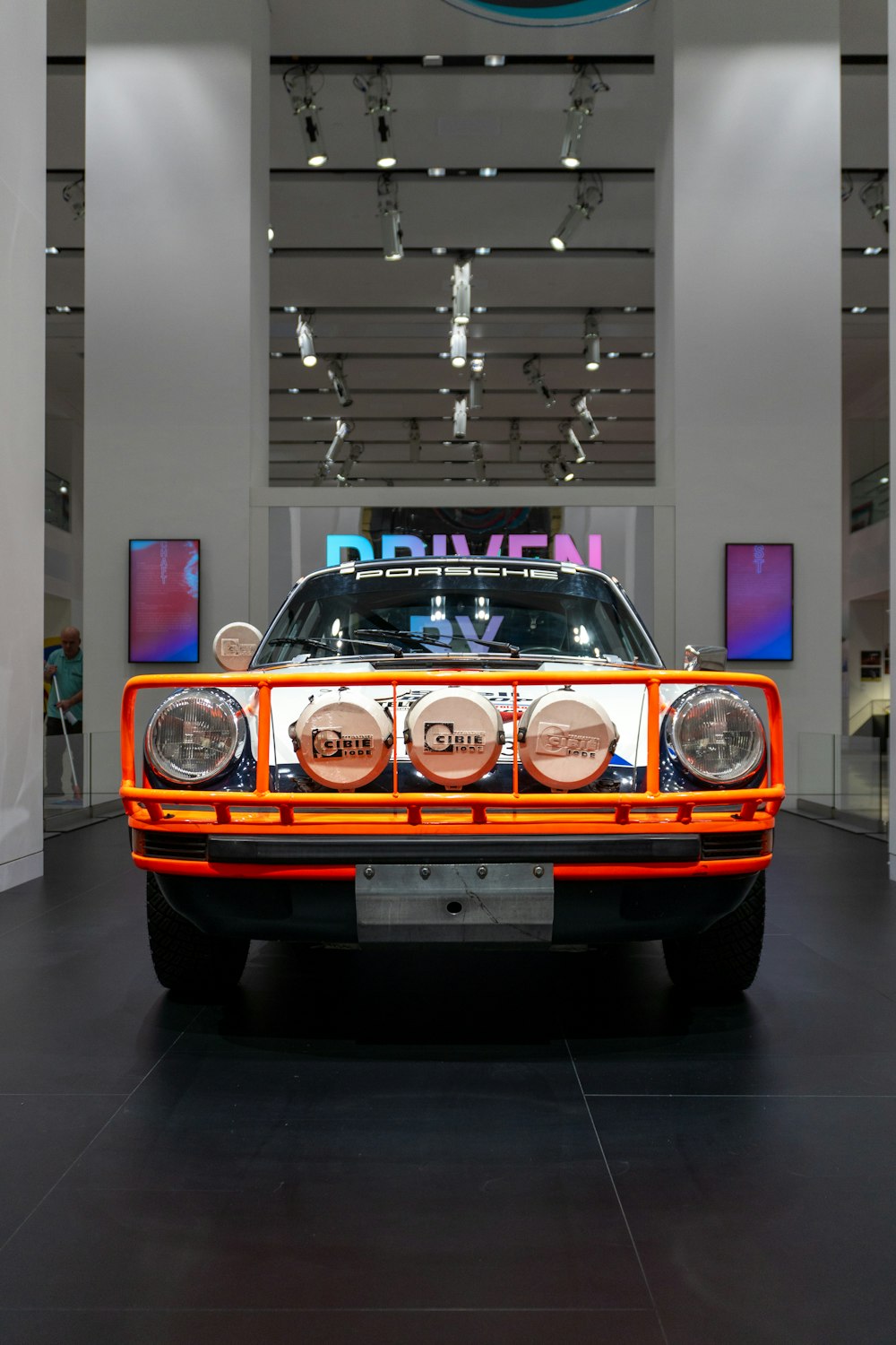 an orange and white car on display in a building