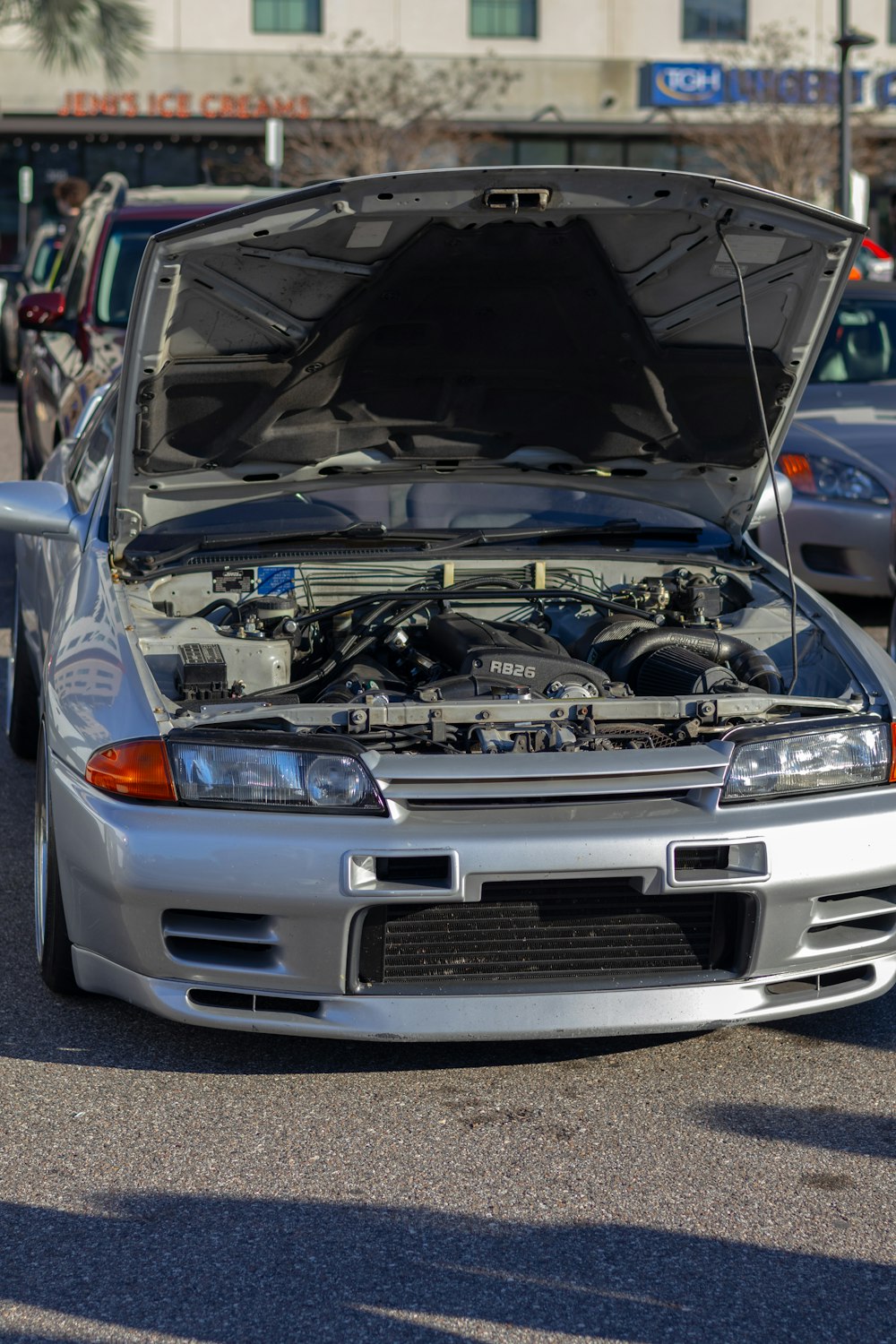 a silver car with its hood open in a parking lot