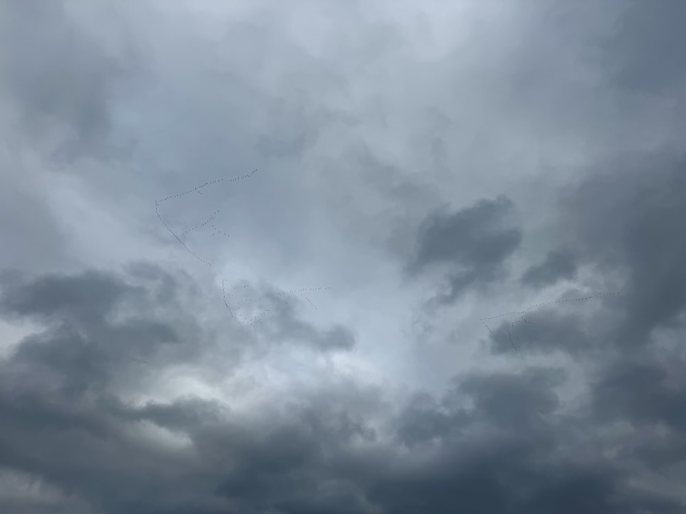 a cloudy sky with a kite flying in the distance