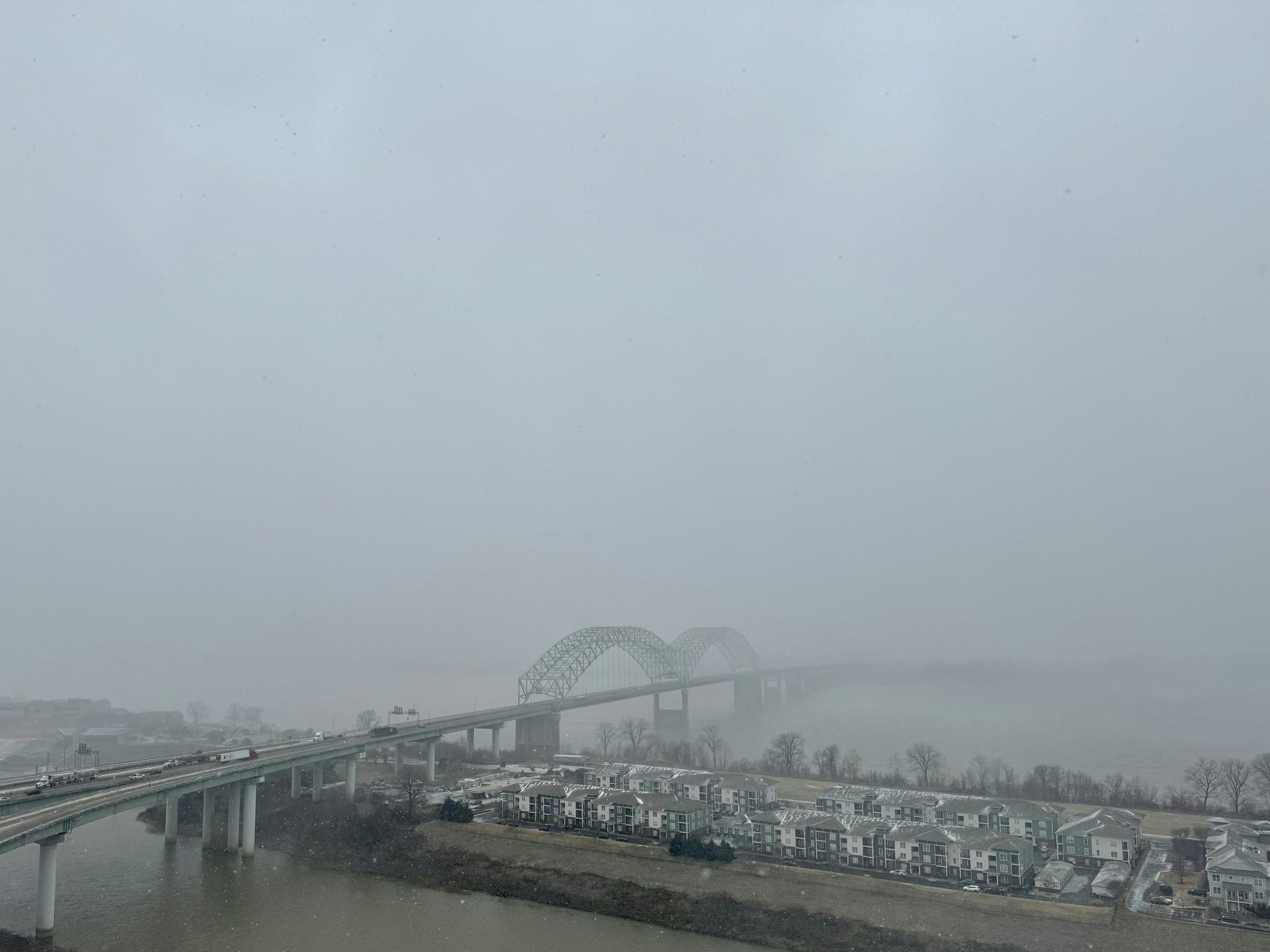 a view of a bridge over a river in the fog
