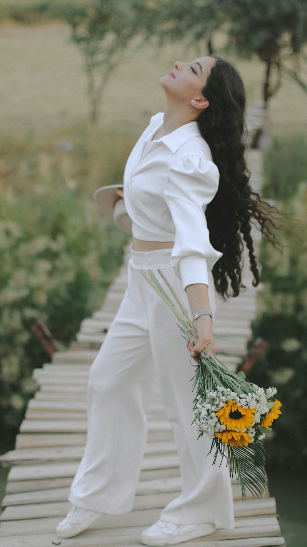 a woman standing on a bridge holding a bouquet of flowers