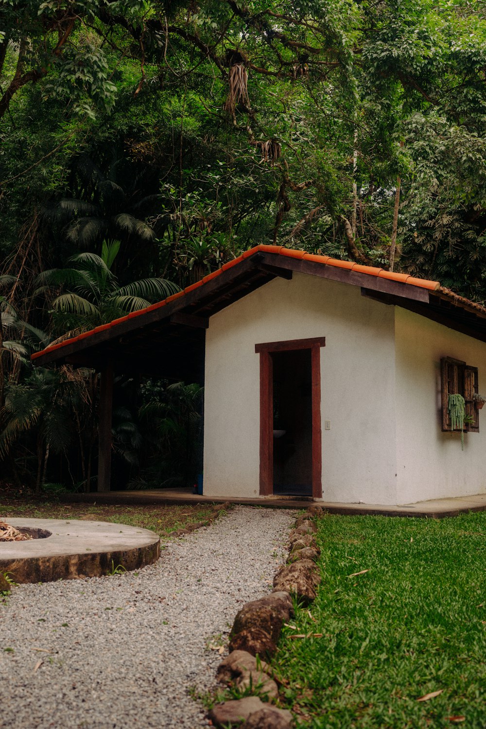 a small white building sitting in the middle of a forest