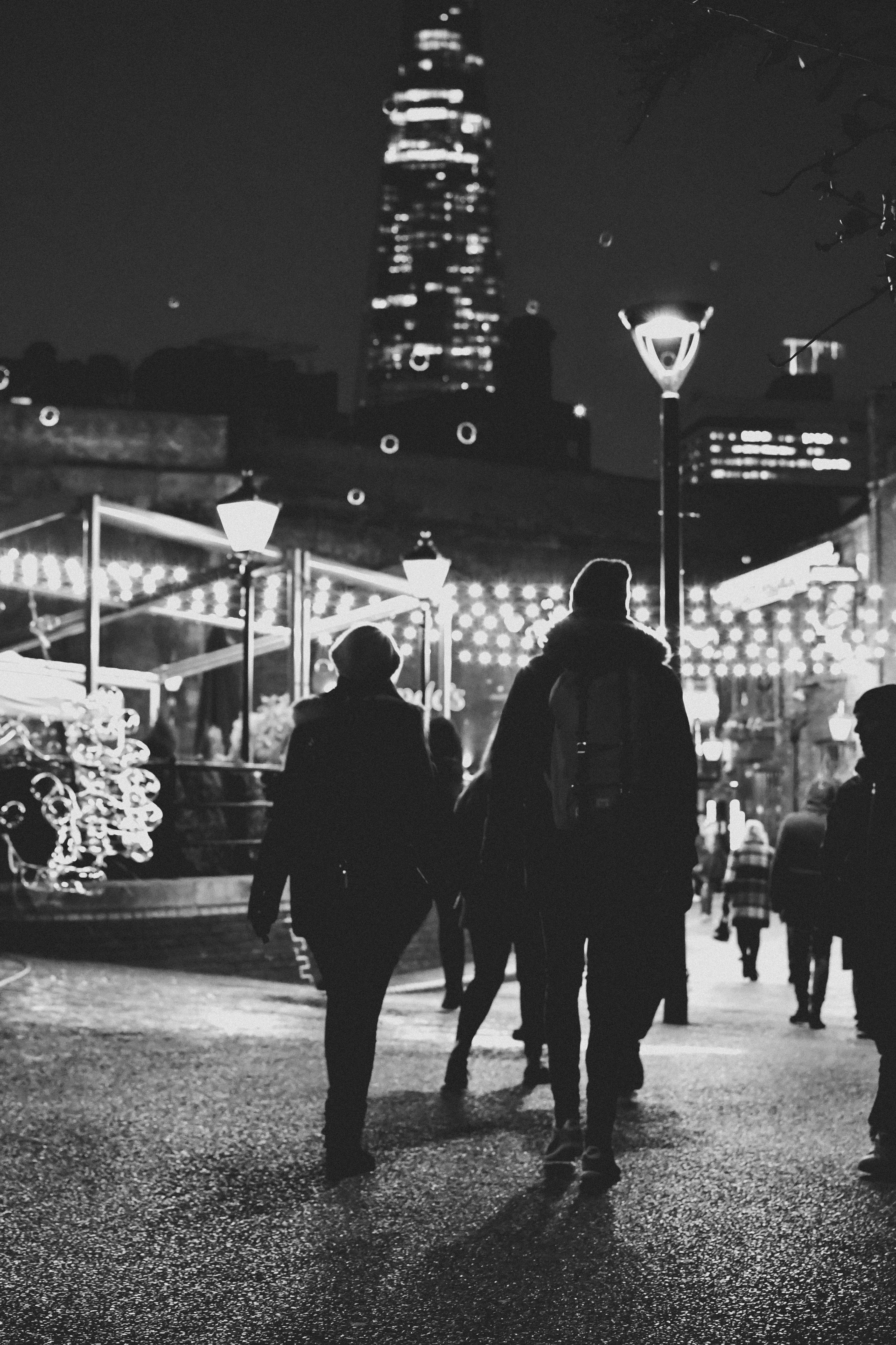 a group of people walking down a street at night