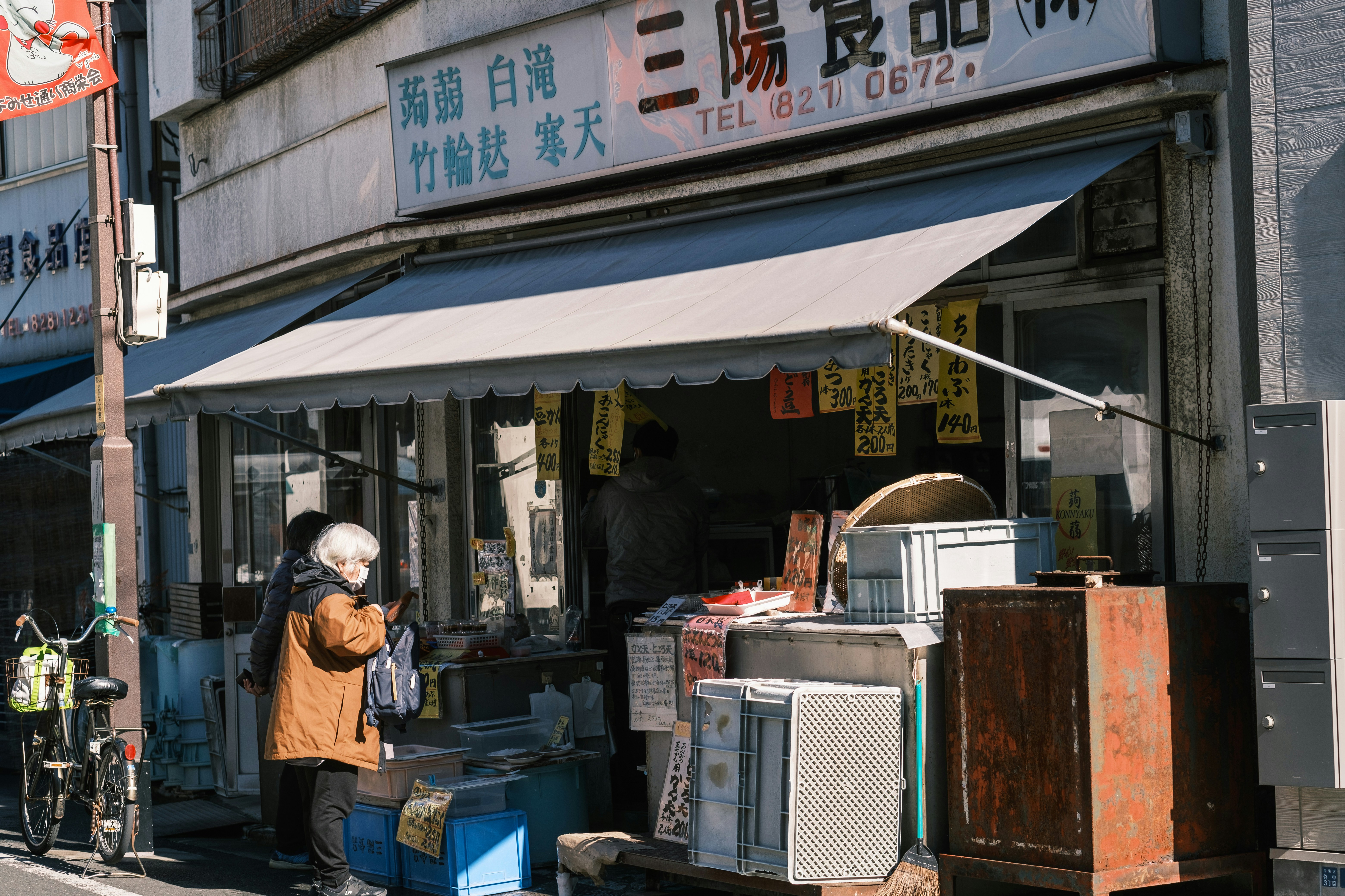 Person checking phone for store hours in front of a closed shop