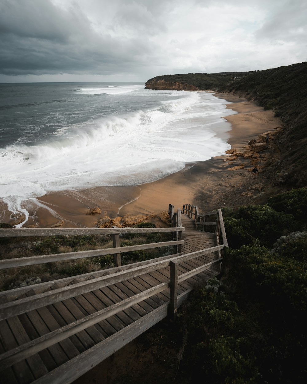 a wooden walkway leading to a beach next to the ocean