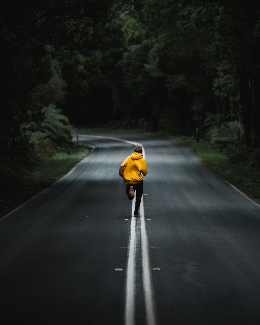 a person in a yellow jacket is skateboarding down a road