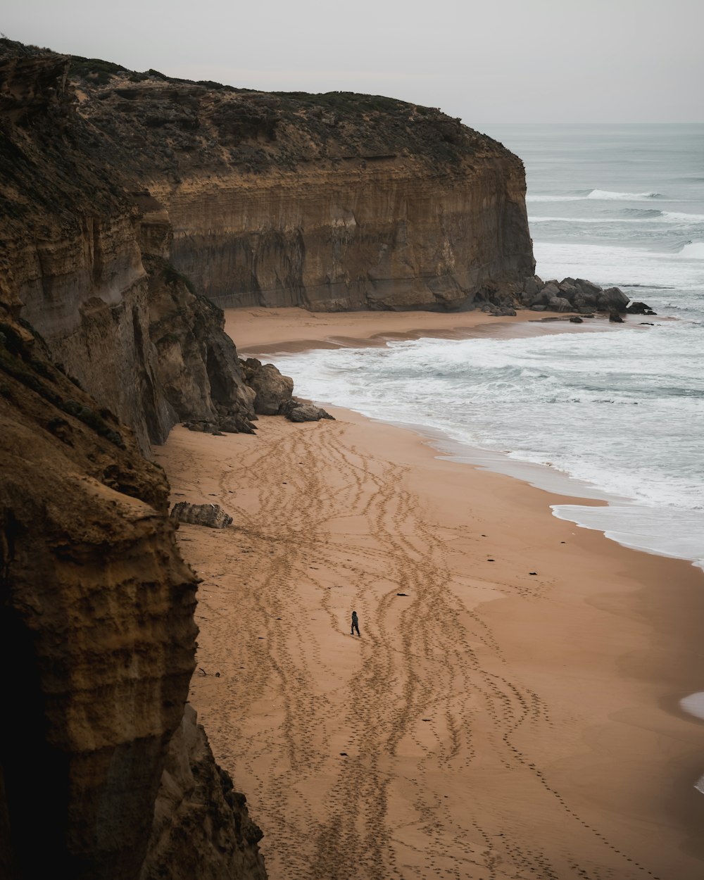 a person walking along a sandy beach next to the ocean