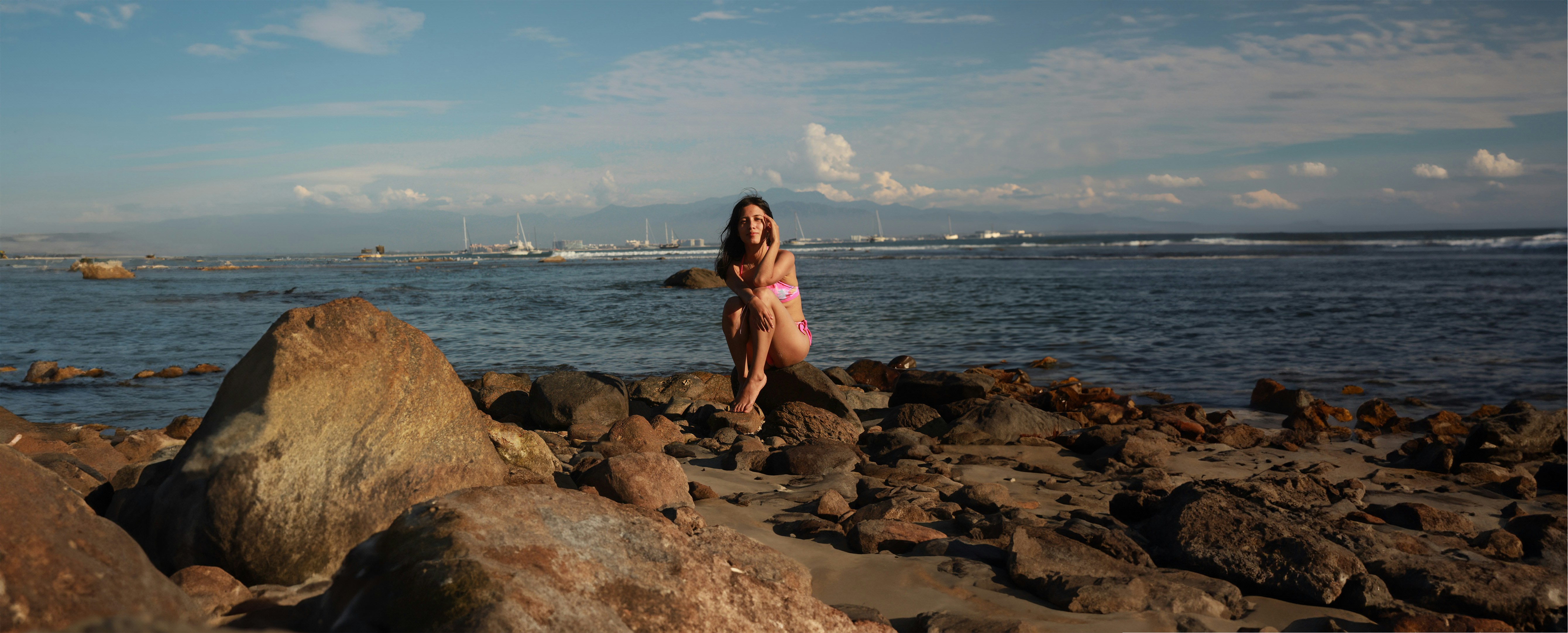a woman standing on a rocky beach next to the ocean