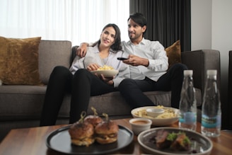 a man and woman sitting on a couch watching tv