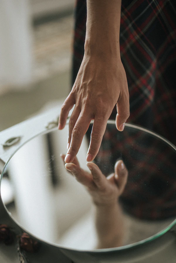 A man adjusting his collar in front of a mirror