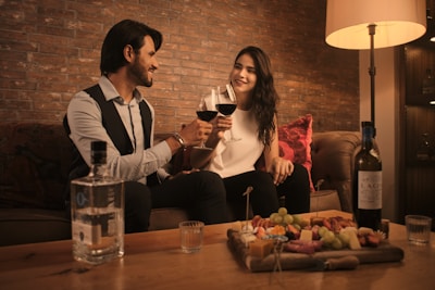 a man and a woman sitting on a couch holding wine glasses