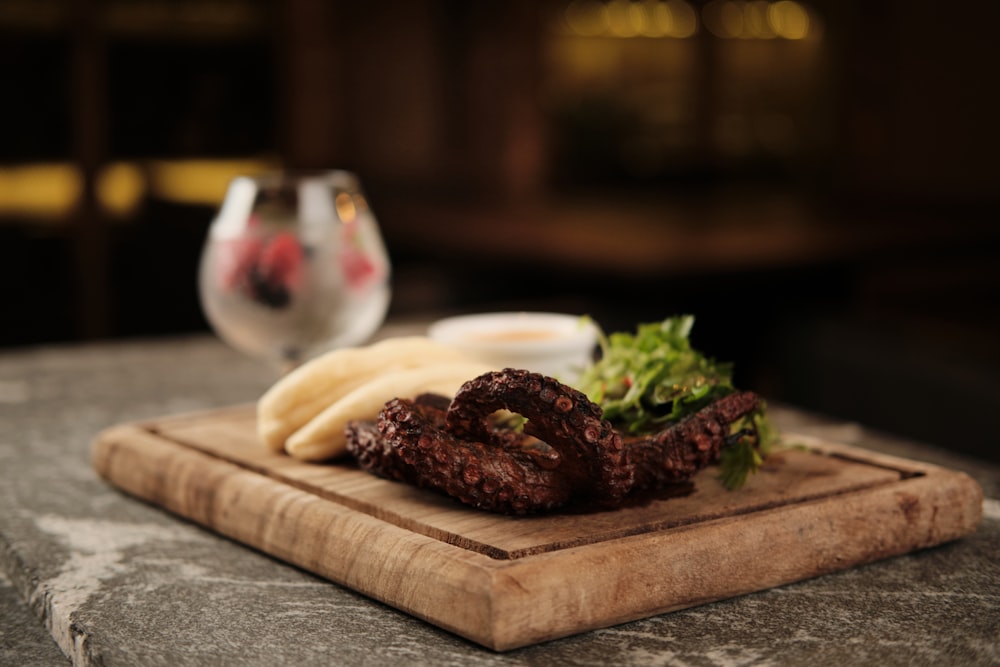 a wooden cutting board topped with meat and veggies