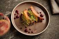 a plate of food on a table next to a glass of wine