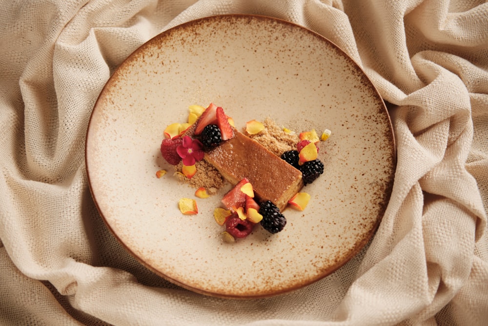 a white plate topped with a piece of cake and fruit