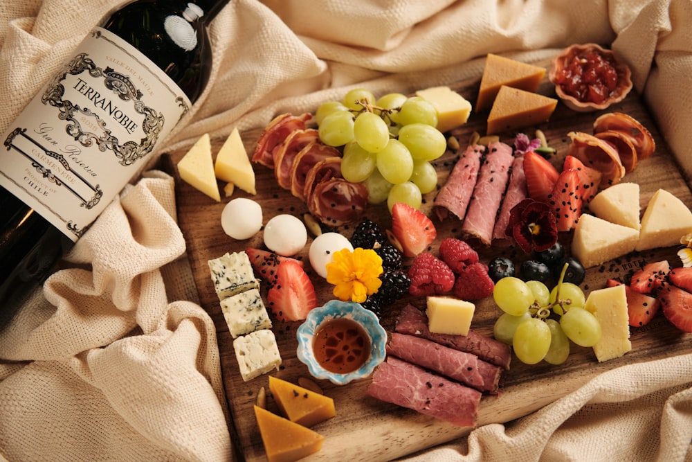 a wooden board topped with lots of different types of cheese