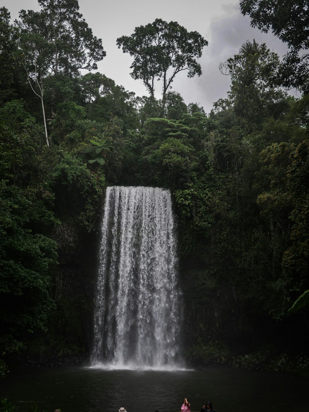 a group of people standing in front of a waterfall