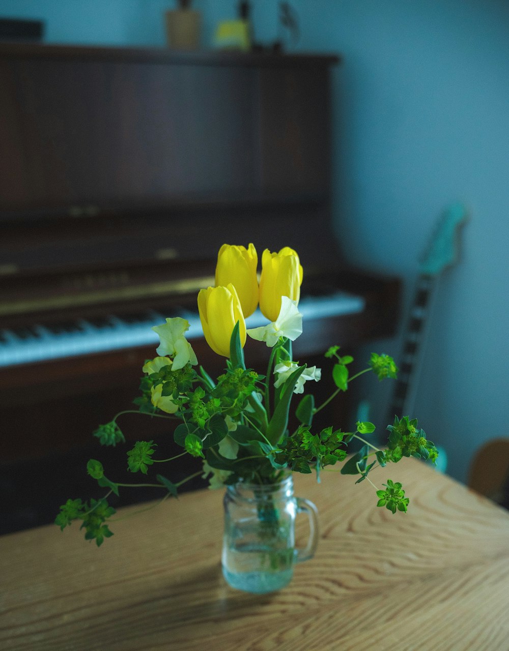 eine Vase mit gelben Blumen auf einem Tisch