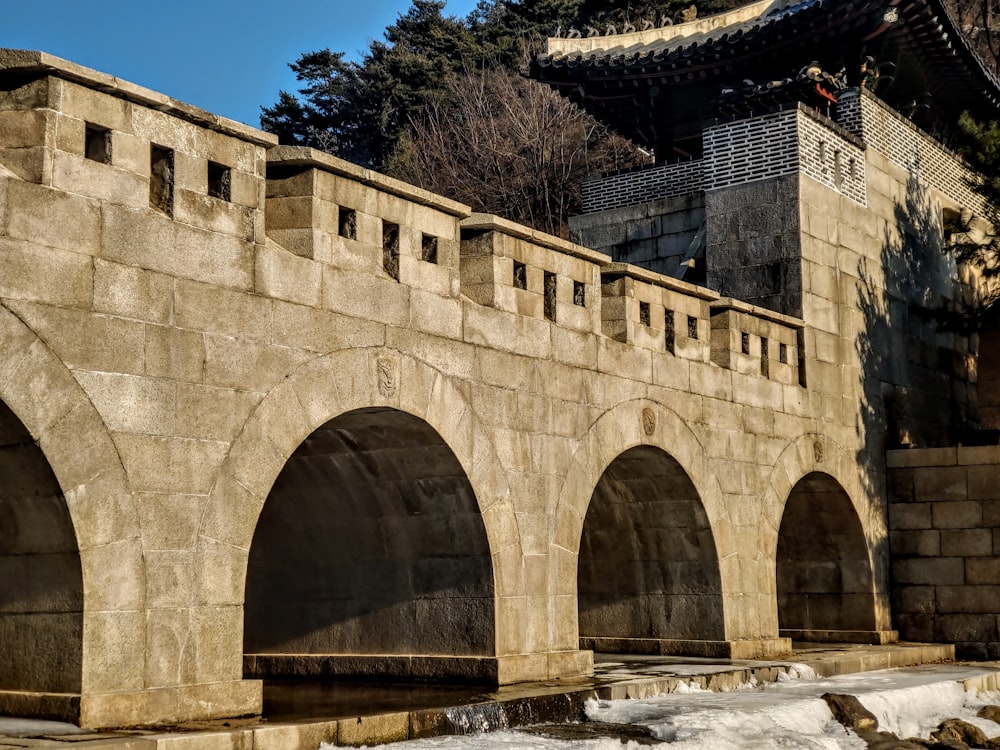 a stone wall with arches and a building in the background