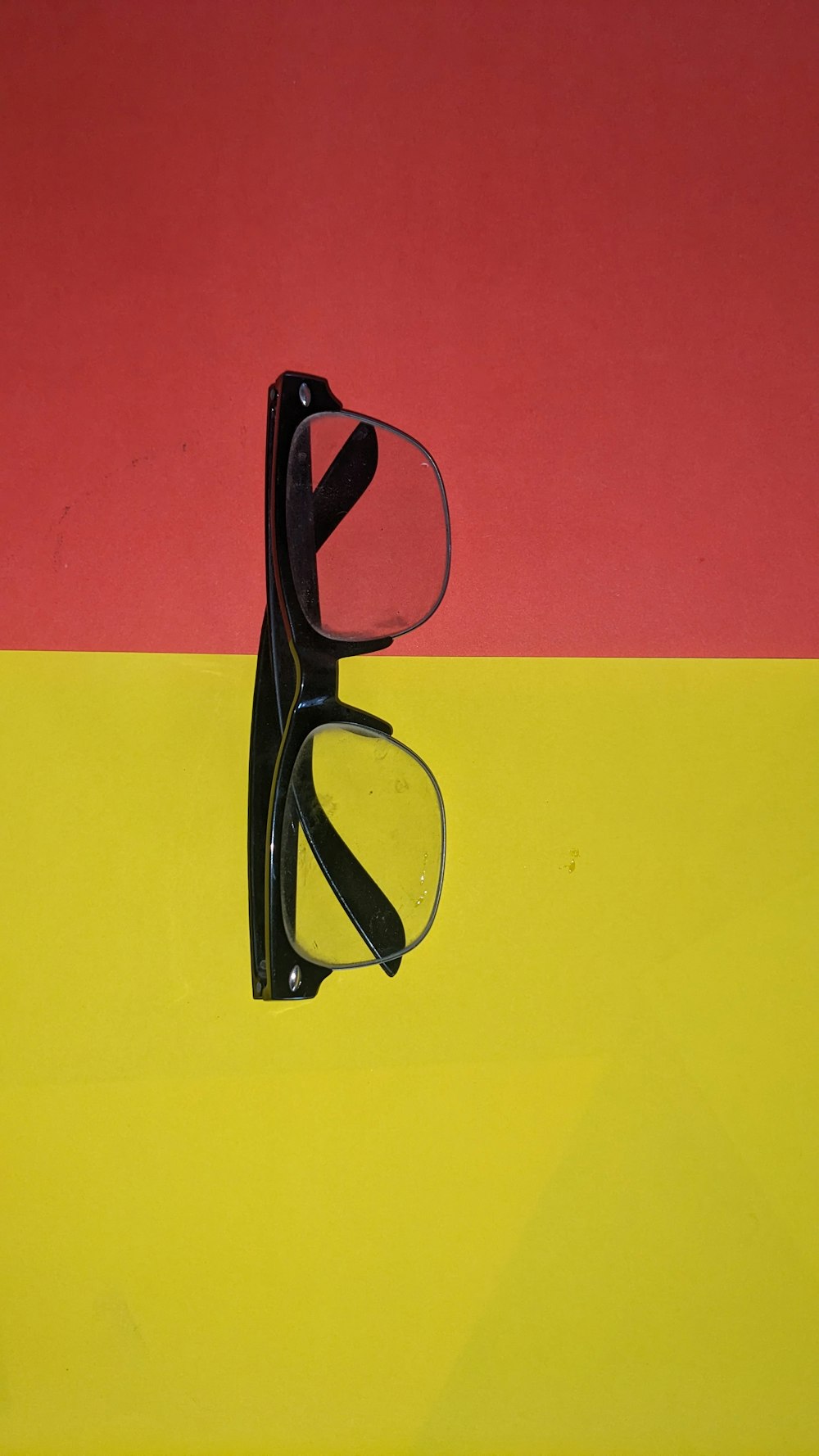 a pair of glasses sitting on top of a yellow and red background