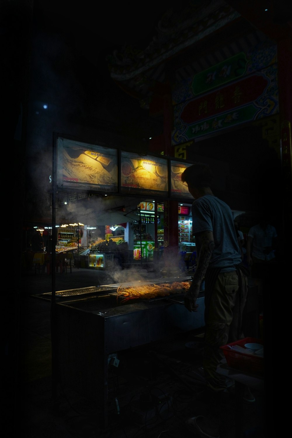 a man standing in front of a food stand at night