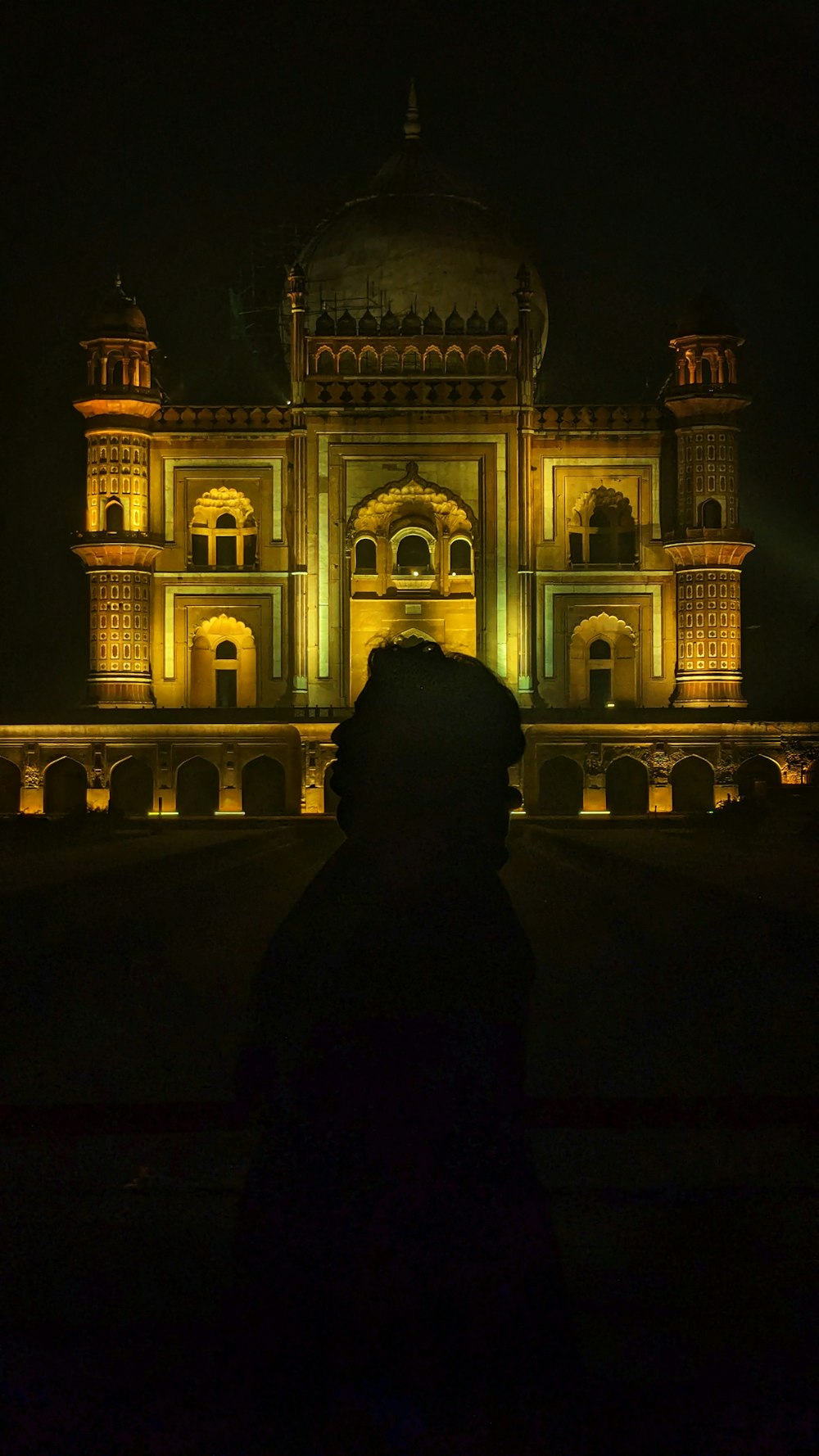 una persona in piedi di fronte a un edificio di notte