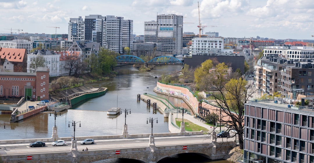a river running through a city next to tall buildings, Wrocław residental district. Construction side. Editorial.