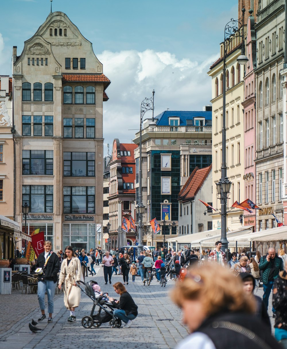 eine Menschenmenge, die eine Straße neben hohen Gebäuden entlanggeht