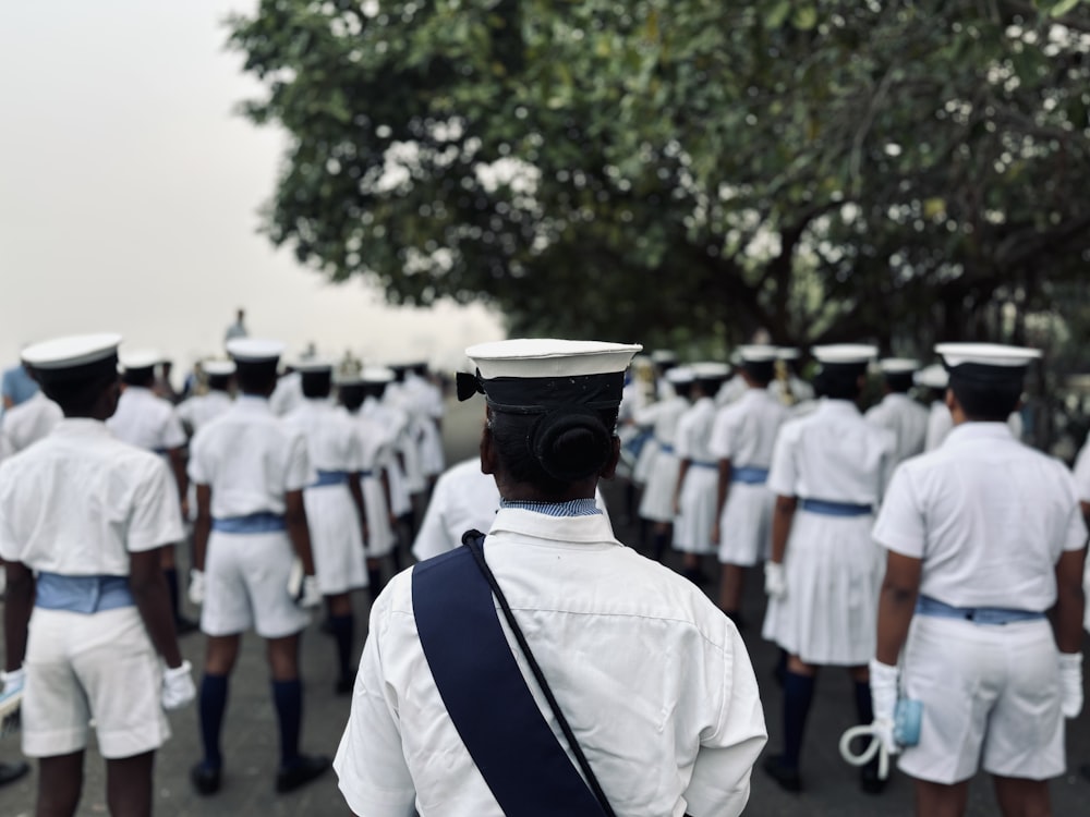a group of men in white uniforms walking down a street