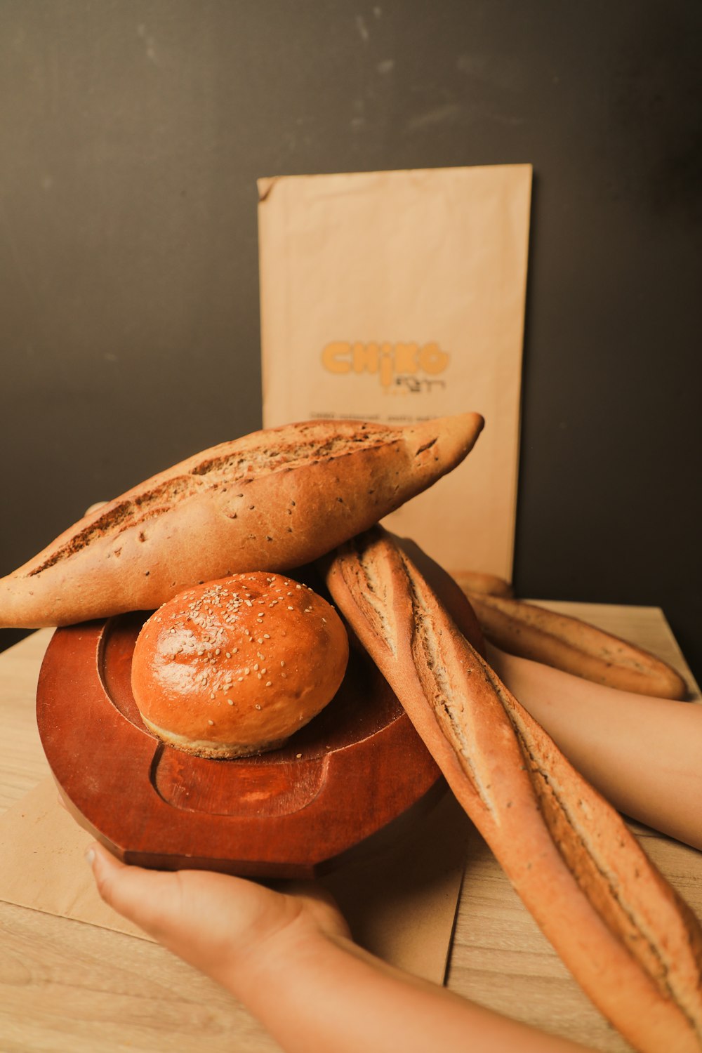 a person holding a wooden bowl with bread on it