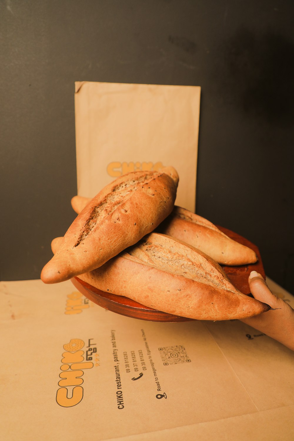 a person holding a plate of bread on top of a table