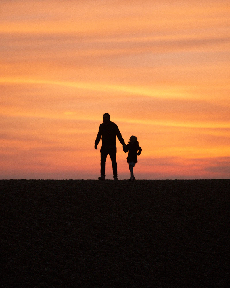 Father and daughter holding hands at sunset