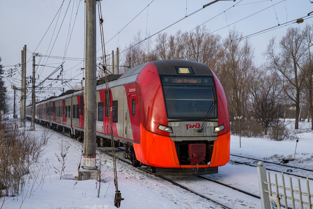 a red train traveling down train tracks next to a forest