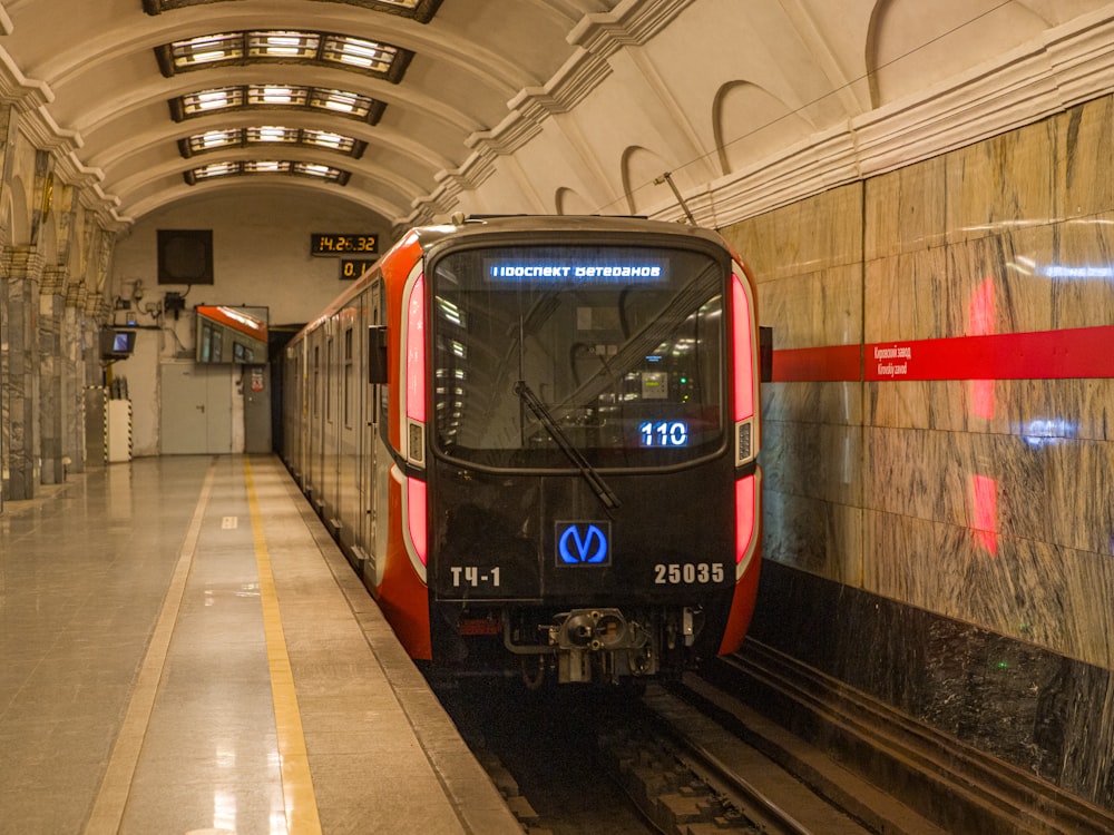 a red and black train pulling into a train station