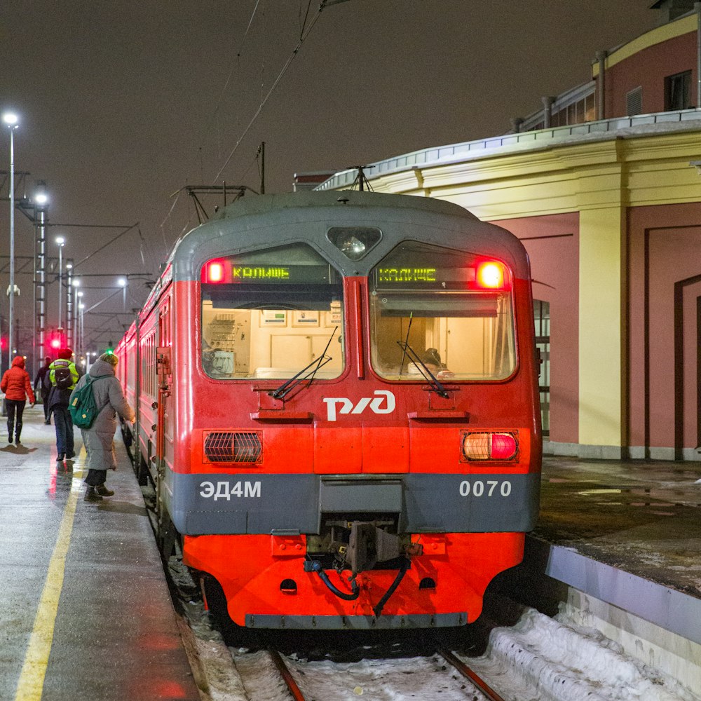 a red and grey train pulling into a train station