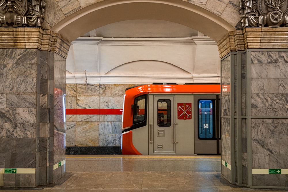 an orange and white train is coming out of a tunnel