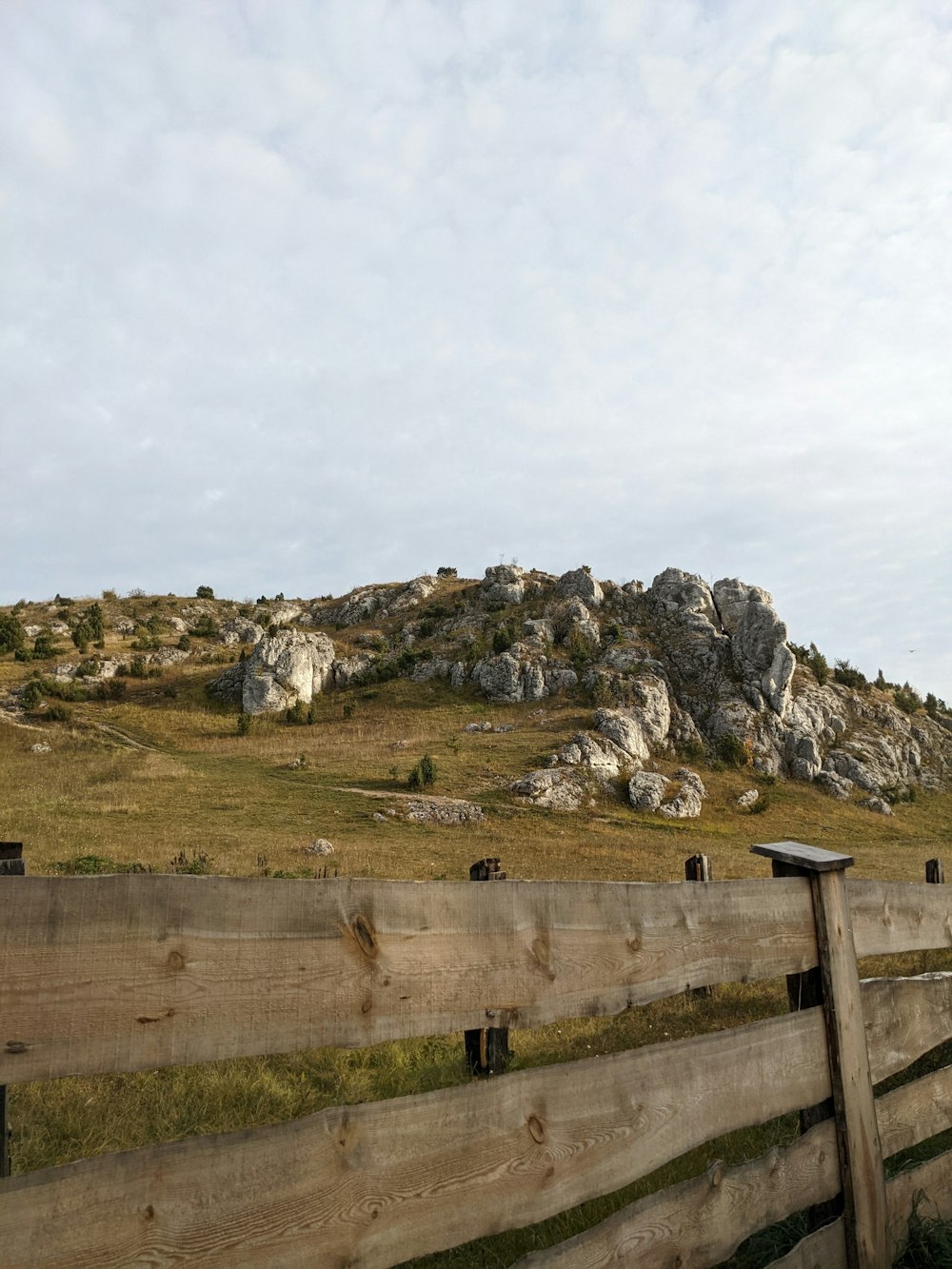 a wooden fence in front of a grassy hill