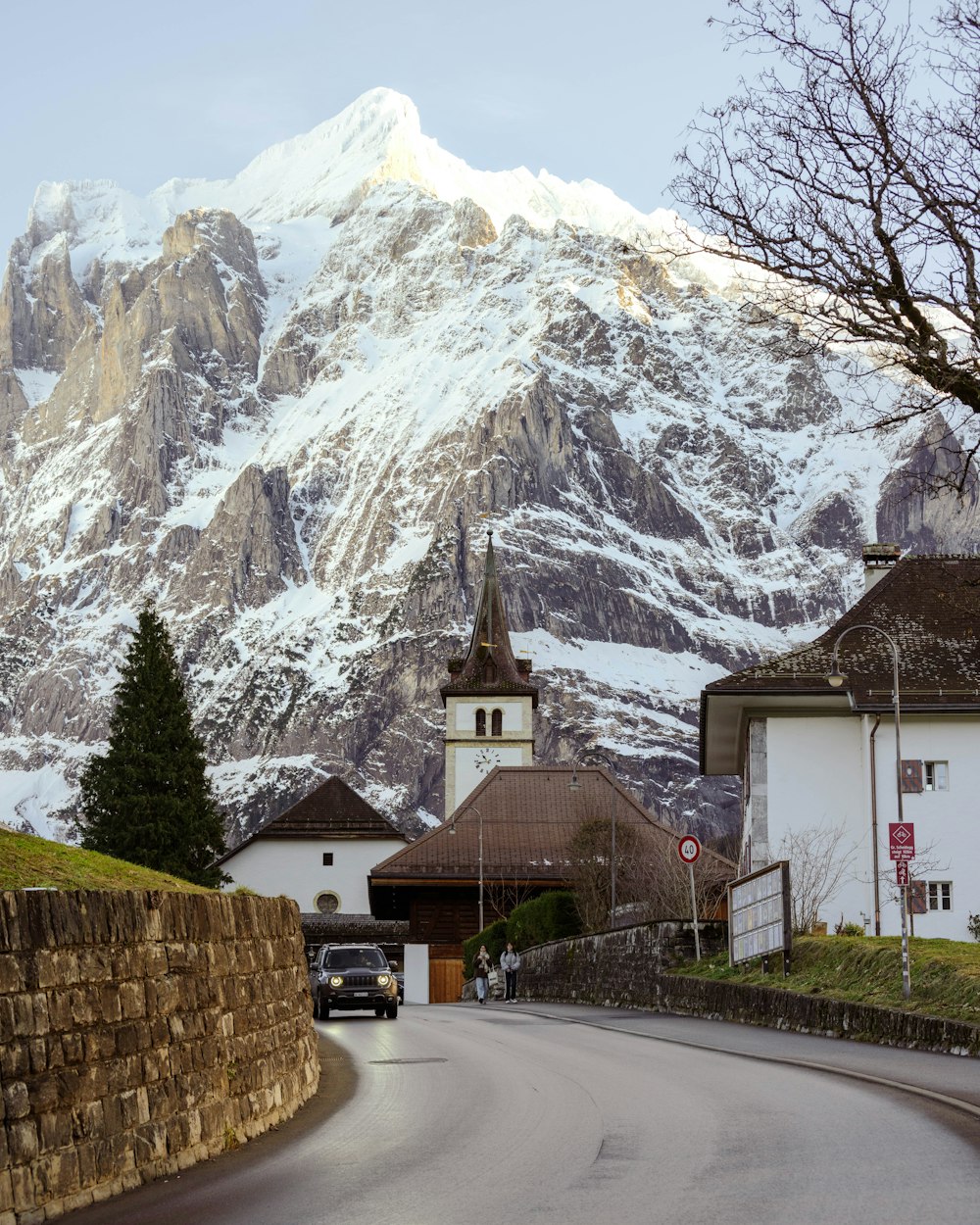 a car driving down a road in front of a snow covered mountain