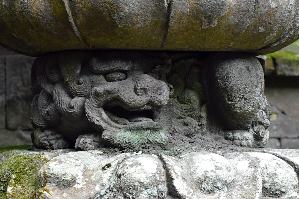 a close up of a stone sculpture with moss growing on it