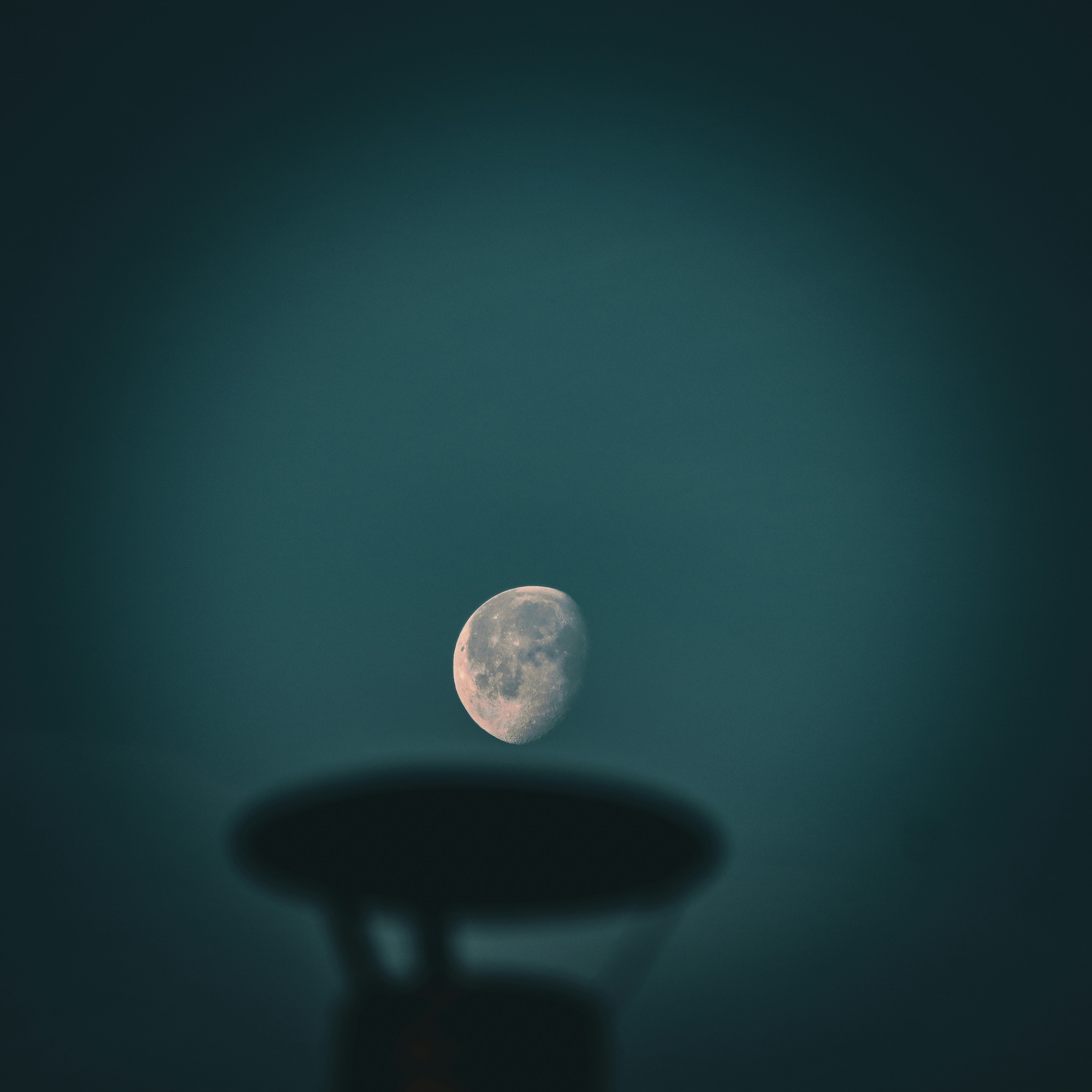 a full moon rising over a table in a dark room