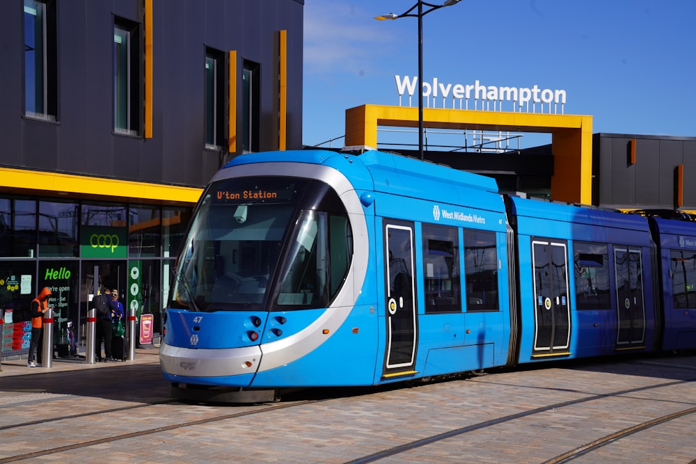 a blue and white train parked in front of a building