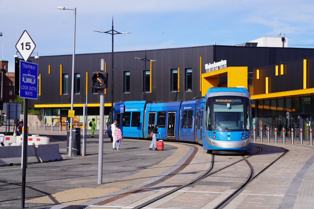 a blue and yellow train traveling past a tall building