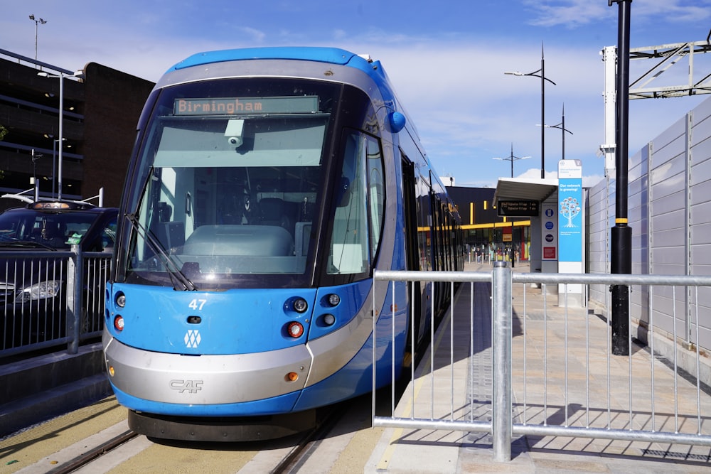 a blue and silver train stopped at a train station