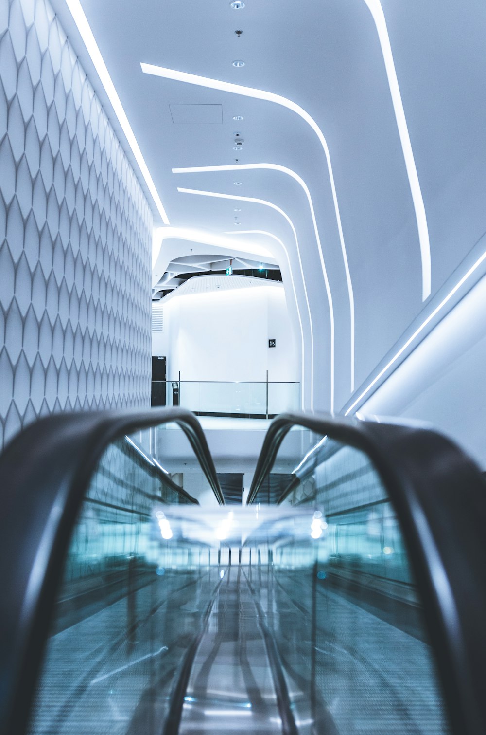an escalator in a building with a white wall