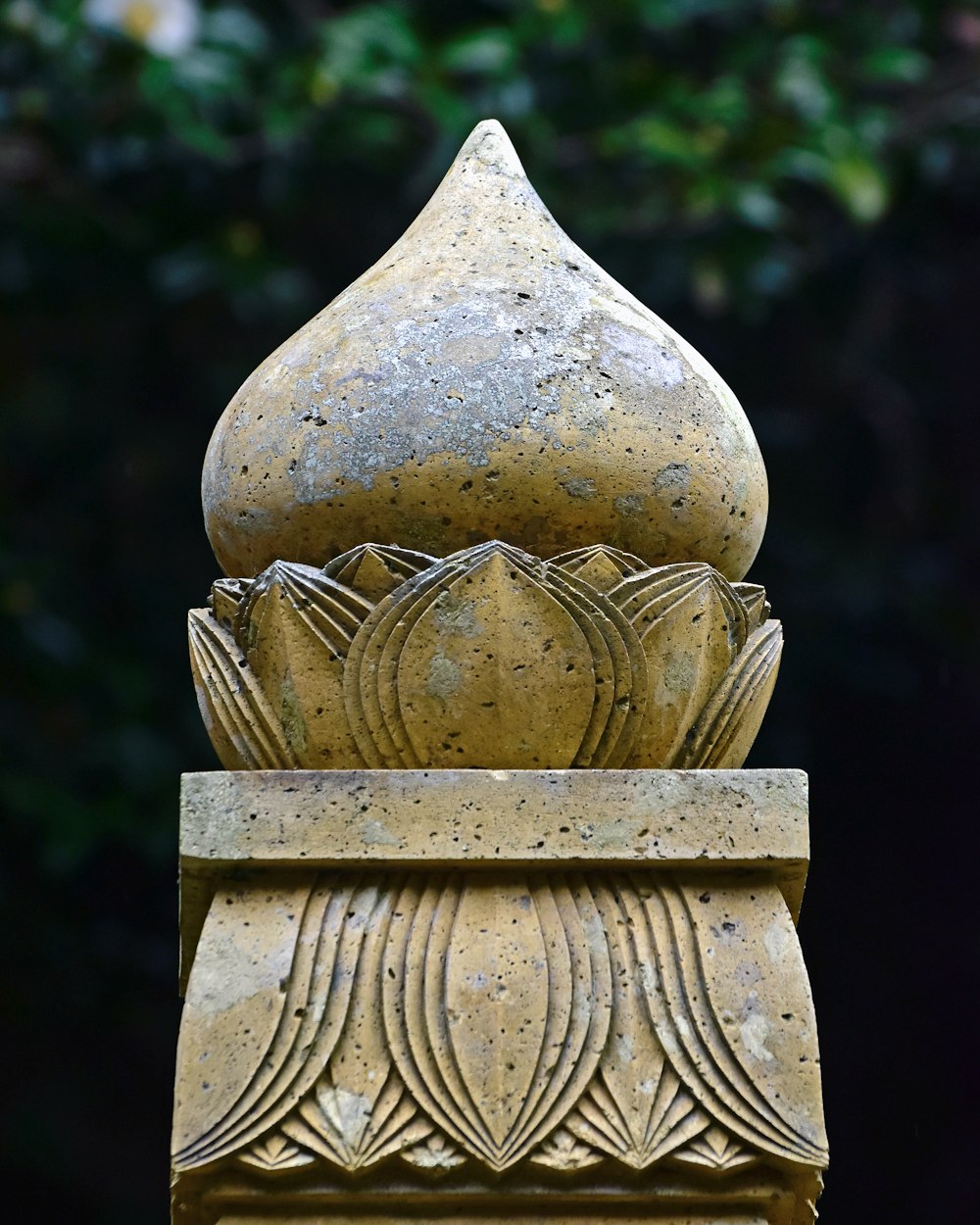 Un primer plano de una estatua con un árbol en el fondo