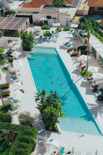 an aerial view of a resort pool with lounge chairs and umbrellas