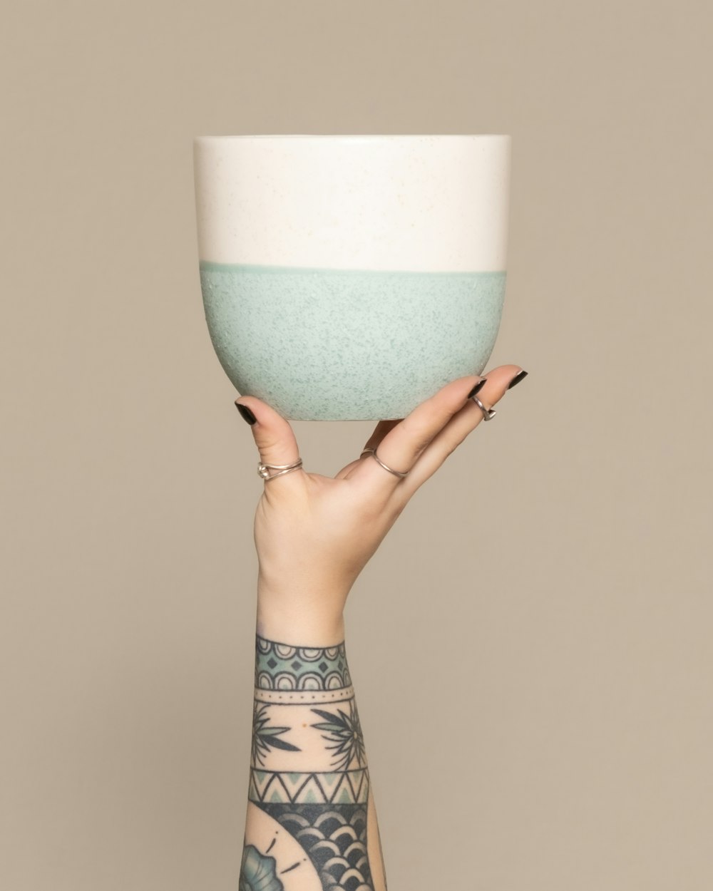 a woman's hand holding a bowl with a tattoo on it
