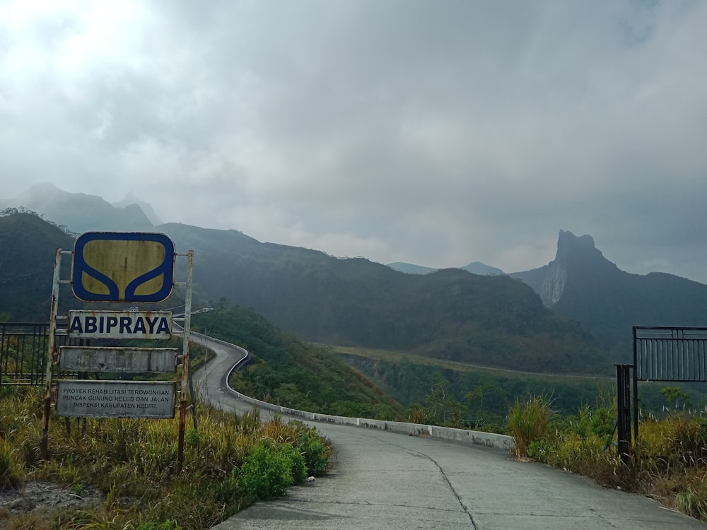 a sign on the side of a road with mountains in the background