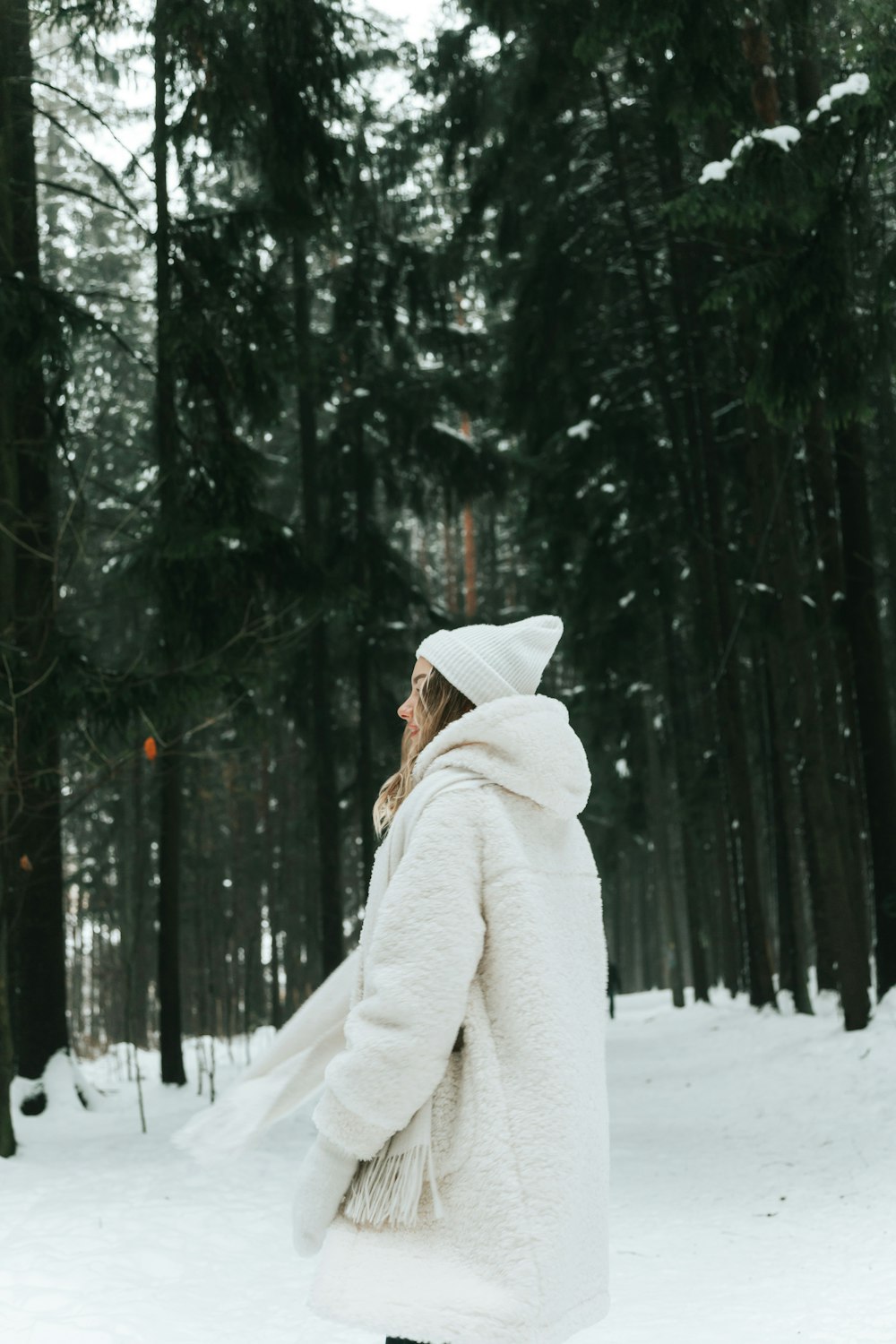 a woman standing in the snow wearing a white coat